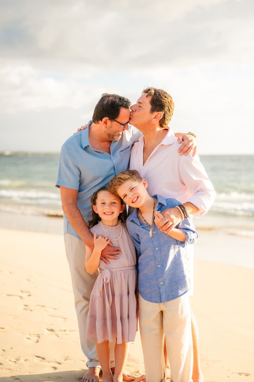 A man kissing a couple of children on a beach during a Hawaii photo session with kids.