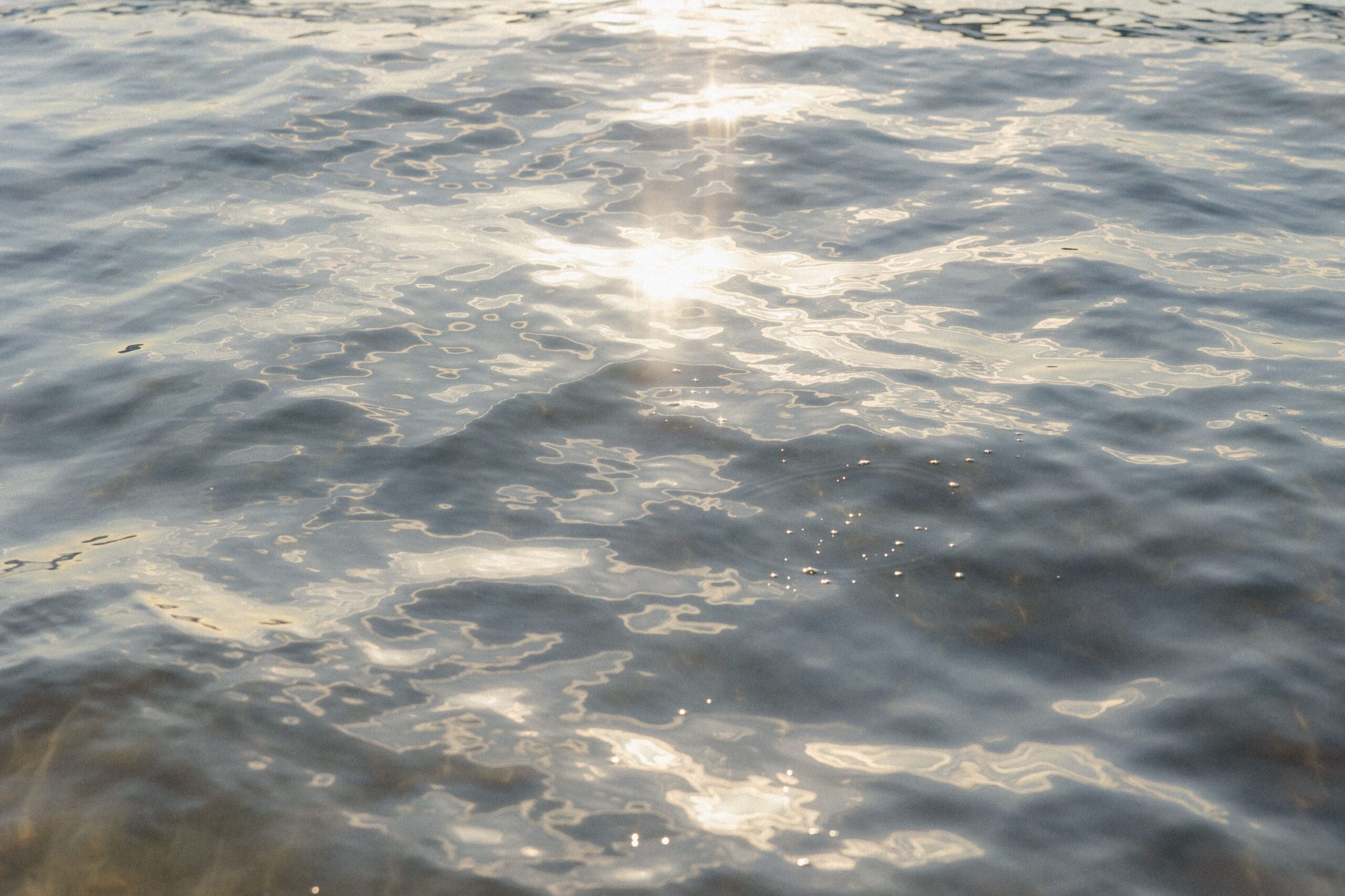 Sunlight reflects off the gentle, rippling surface of calm water, creating shimmering patterns and a serene, peaceful atmosphere—an inviting scene that embodies the tranquility valued in Hawaii cultural etiquette.